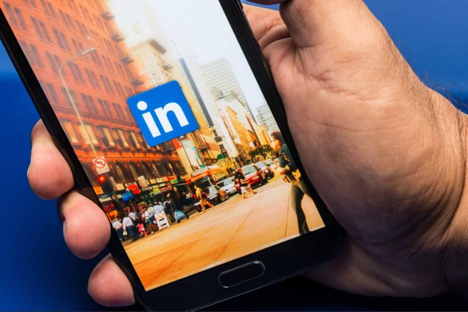 algoritmo do linkedin: imagem de uma mão segurando um celular com a tela do linkedin aberta