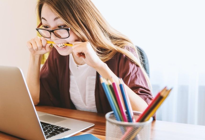 Faculdades de marketing: imagem de uma menina olhando para a tela do notebook com um lápis na boca