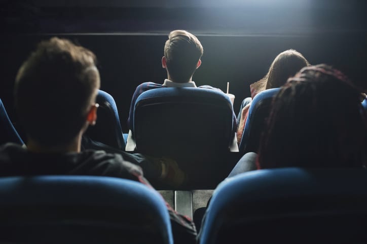 Imagem com pessoas de costas vendo filmes de marketing no cinema