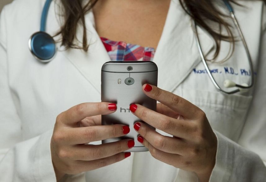 Marketing digital para médicos: imagem de uma mulher usando um jaleco e mexendo no celular