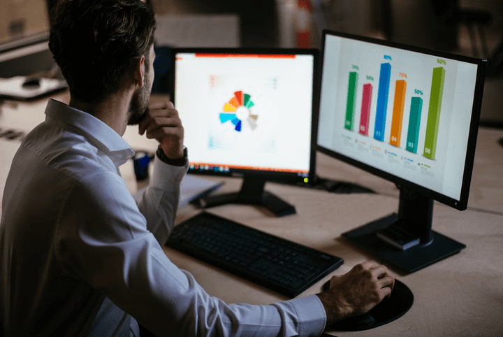 social analytics: imagem com uma pessoa analisando dados e gráficos em dois computadores
